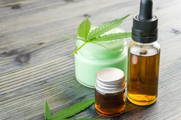 CBD cream and oils in small containers, hemp leaves